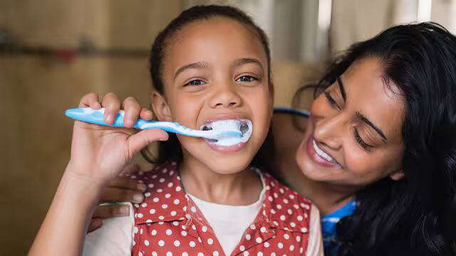 Madre e hija cepillando sus dientes