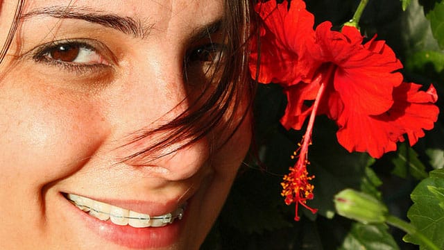 mujer sonriendo a la cámara con una flor
