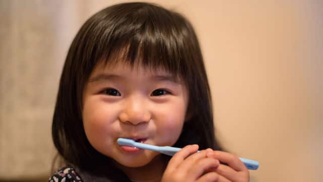 Niña cepillandose los dientes feliz