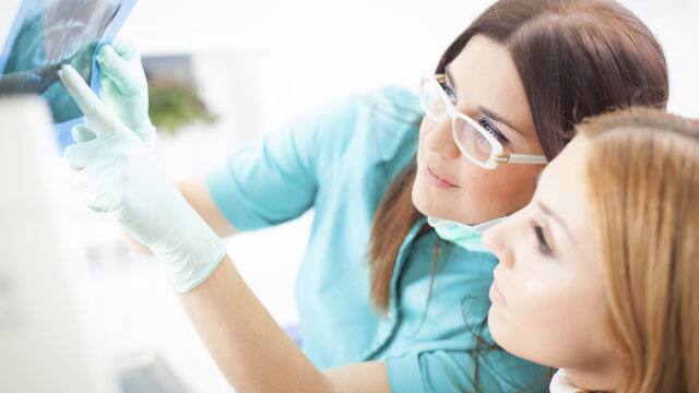 Mujer y su dentista viendo radiografía bucal