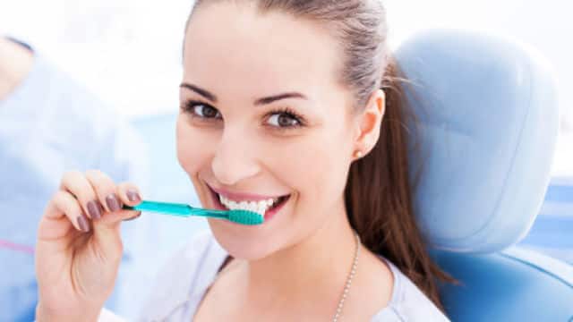 Mujer sonriendo cepillandose los dientes