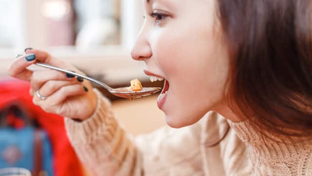 Mujer joven tomando un plato de sopas