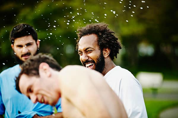 man smiling in a white tshirt enjoying himself outside with his freinds