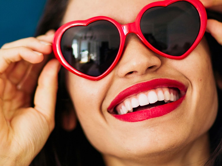 woman wearing heart shaped sunglasses showing white teeth