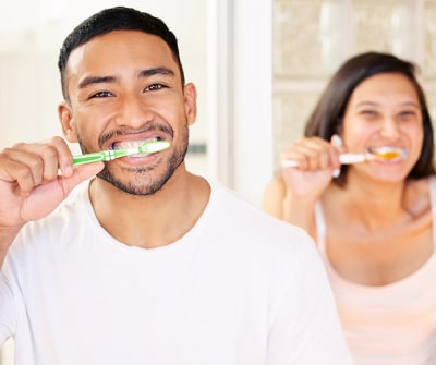 Hombre y mujer cepillando sus dientes