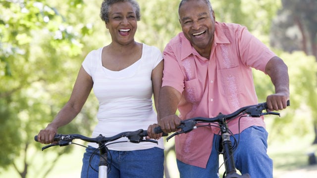 Elderly couple laughing while riding a bicycle