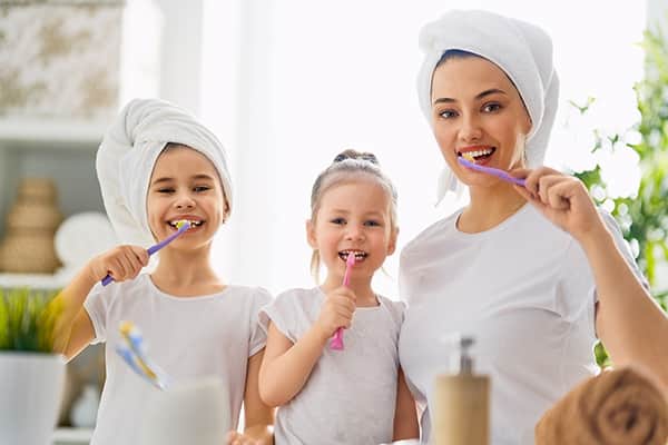 Familia en toalla cepillandose los dientes