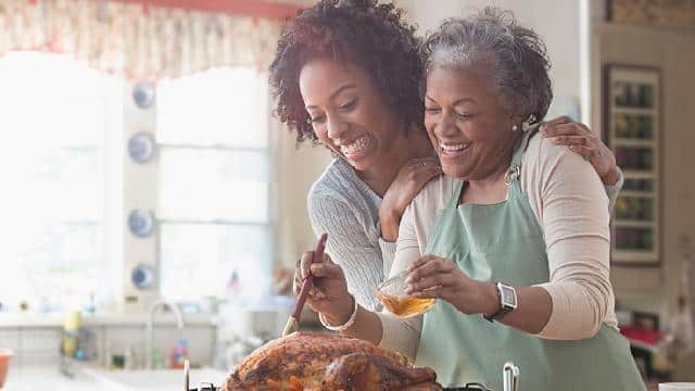 Mother and daughter basting turkey