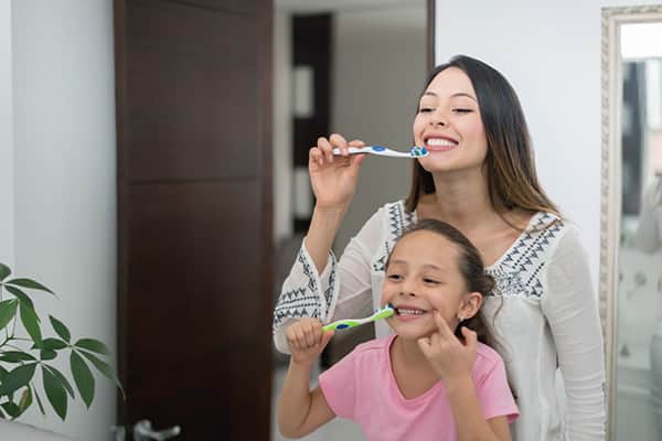 Una madre y su hija que se cepillan los dientes en el baño