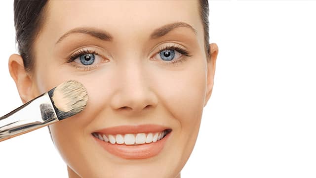 Mujer maquillandose y sonriendo