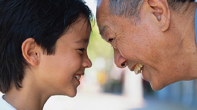 elderly Asian man smiling at child
