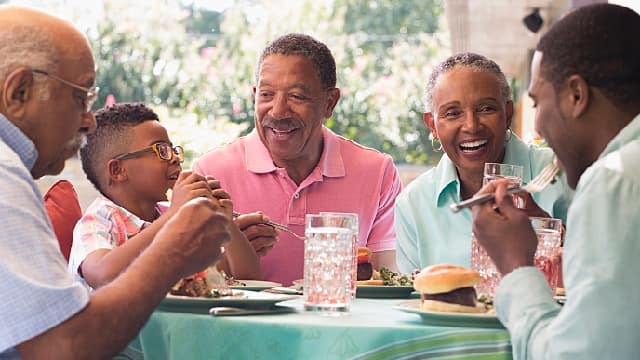 A family enjoying a meal while smiling brightly